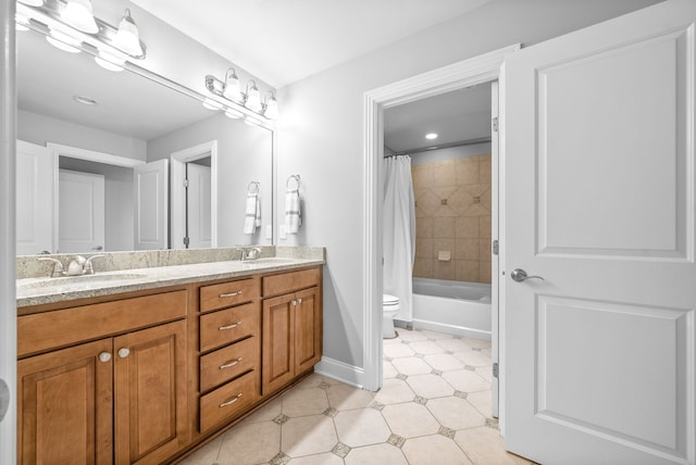 bathroom featuring double vanity, toilet, baseboards, and a sink