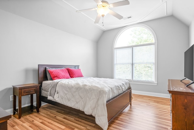 bedroom with visible vents, light wood-type flooring, baseboards, and vaulted ceiling