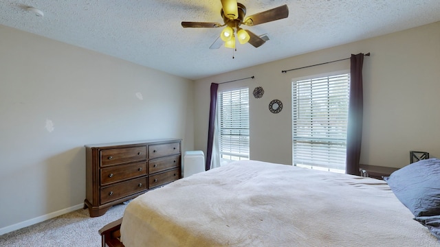 bedroom featuring light colored carpet, ceiling fan, and a textured ceiling