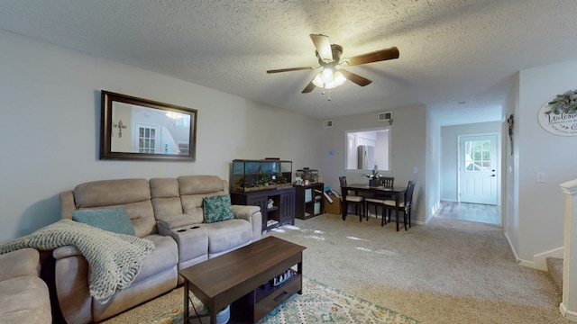 carpeted living room featuring ceiling fan and a textured ceiling