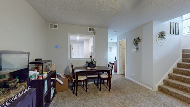 dining area with light colored carpet and a textured ceiling