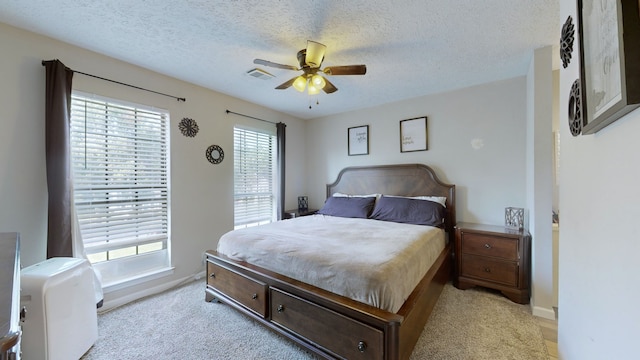 carpeted bedroom featuring multiple windows, a textured ceiling, and ceiling fan