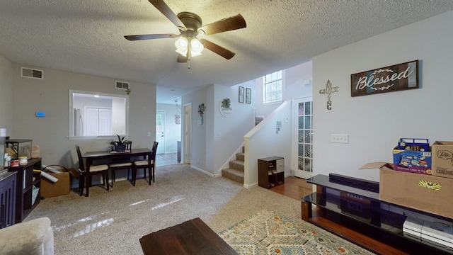 living room with a textured ceiling, carpet, and ceiling fan