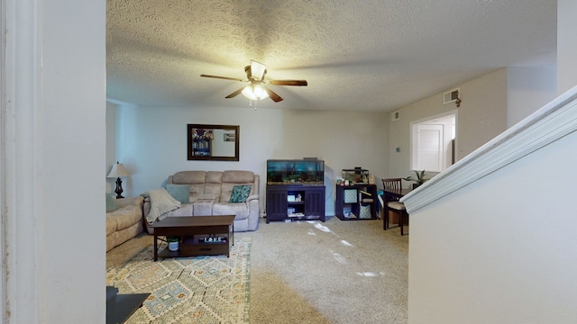 living room featuring carpet flooring, ceiling fan, and a textured ceiling