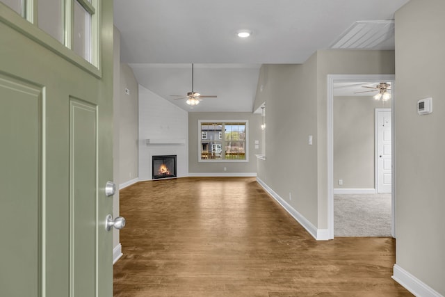 unfurnished living room featuring ceiling fan, a fireplace, wood-type flooring, and vaulted ceiling