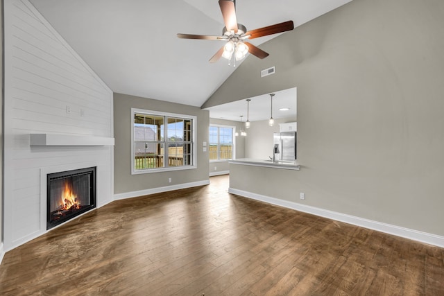 unfurnished living room featuring ceiling fan, sink, high vaulted ceiling, a fireplace, and dark hardwood / wood-style floors