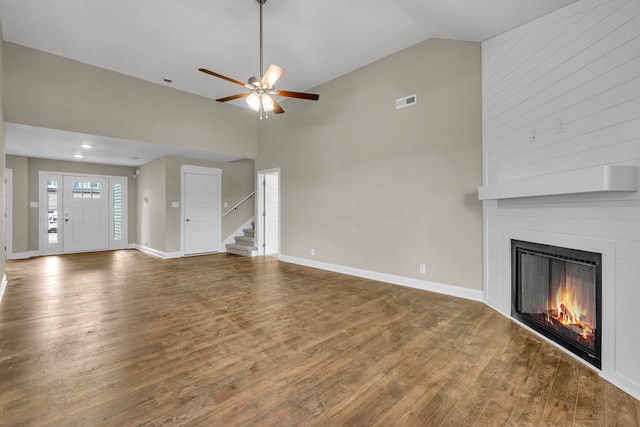 unfurnished living room featuring a large fireplace, hardwood / wood-style flooring, high vaulted ceiling, and ceiling fan