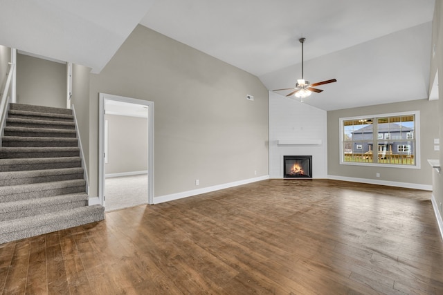 unfurnished living room featuring dark hardwood / wood-style flooring, ceiling fan, a large fireplace, and high vaulted ceiling