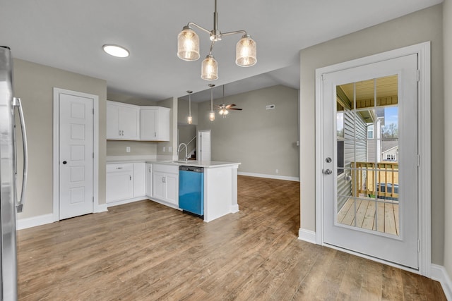 kitchen with hanging light fixtures, kitchen peninsula, lofted ceiling, white cabinets, and hardwood / wood-style flooring