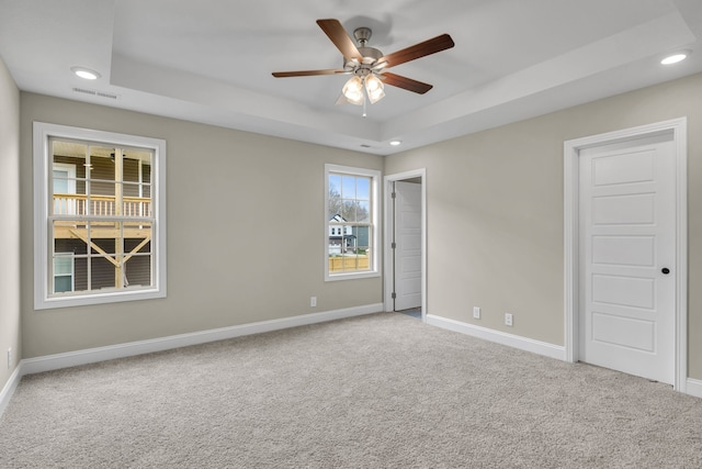 spare room with carpet flooring, ceiling fan, and a tray ceiling