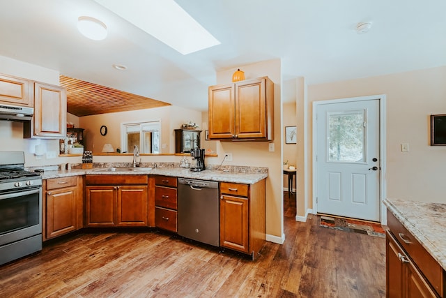 kitchen featuring appliances with stainless steel finishes, dark hardwood / wood-style flooring, a skylight, and sink