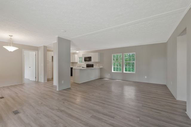 unfurnished living room featuring light wood-type flooring and a textured ceiling