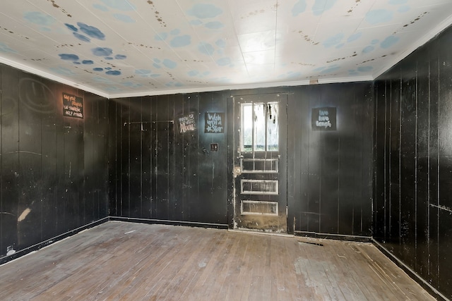 interior space with crown molding, wood-type flooring, and wood walls