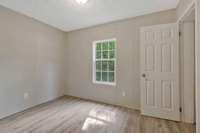 spare room featuring a textured ceiling and light hardwood / wood-style flooring