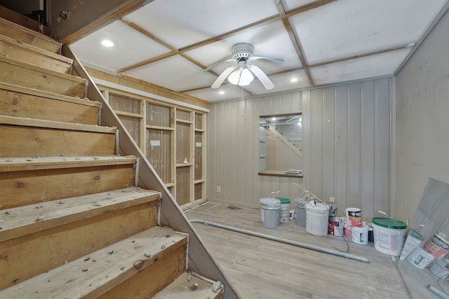 basement featuring wood walls, wood-type flooring, and ceiling fan