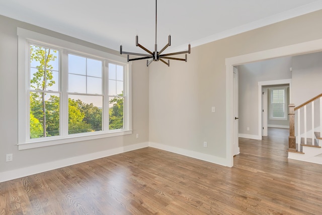 empty room featuring an inviting chandelier and light wood-type flooring