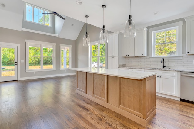 kitchen featuring white cabinetry, light stone countertops, wood-type flooring, dishwasher, and a center island