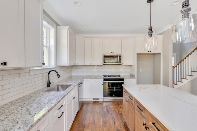 kitchen with white cabinetry, stainless steel appliances, sink, and light stone counters