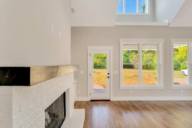 doorway to outside featuring wood-type flooring, a high ceiling, and a brick fireplace