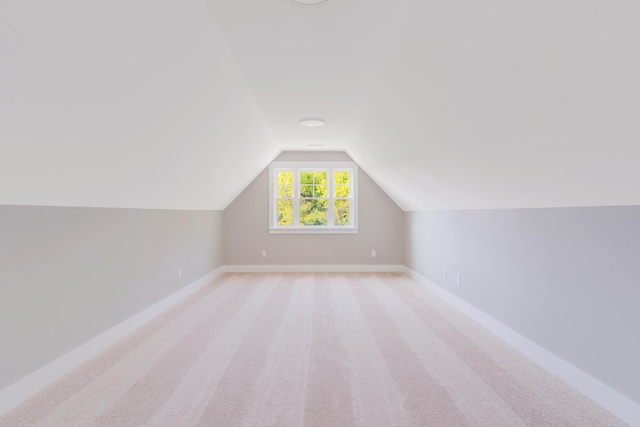 additional living space featuring vaulted ceiling and light colored carpet