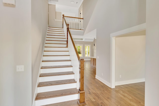 staircase featuring a high ceiling and hardwood / wood-style flooring