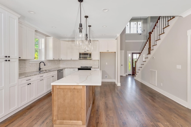 kitchen with appliances with stainless steel finishes, white cabinetry, a healthy amount of sunlight, and a center island