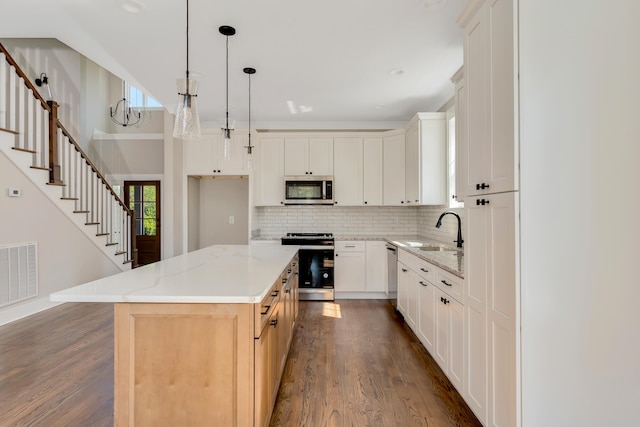 kitchen with a center island, white cabinetry, stainless steel appliances, and wood-type flooring