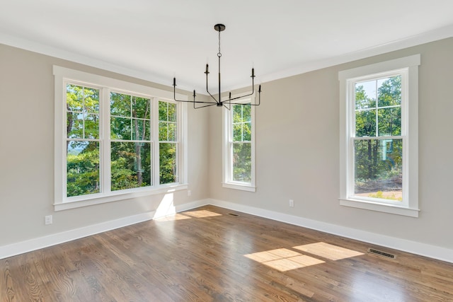 unfurnished dining area featuring an inviting chandelier, wood-type flooring, and crown molding