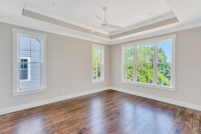 unfurnished room with ornamental molding, dark hardwood / wood-style floors, a tray ceiling, and ceiling fan