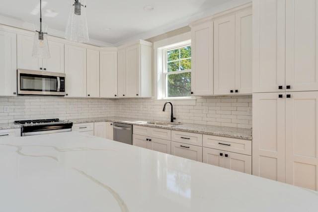 kitchen with decorative backsplash, hanging light fixtures, white cabinetry, sink, and stainless steel appliances