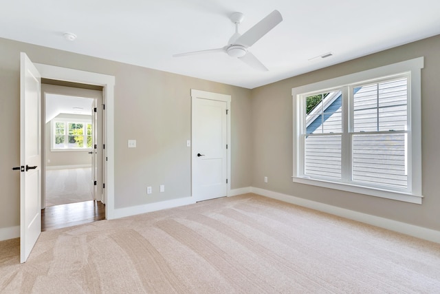 unfurnished bedroom featuring light carpet, multiple windows, and ceiling fan