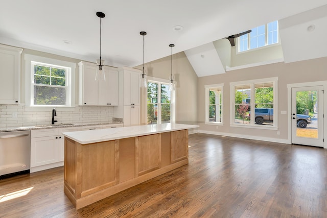 kitchen featuring hardwood / wood-style floors, light stone counters, white cabinetry, stainless steel dishwasher, and a center island