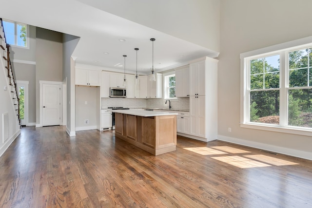 kitchen with white cabinetry, stainless steel appliances, a wealth of natural light, and a kitchen island