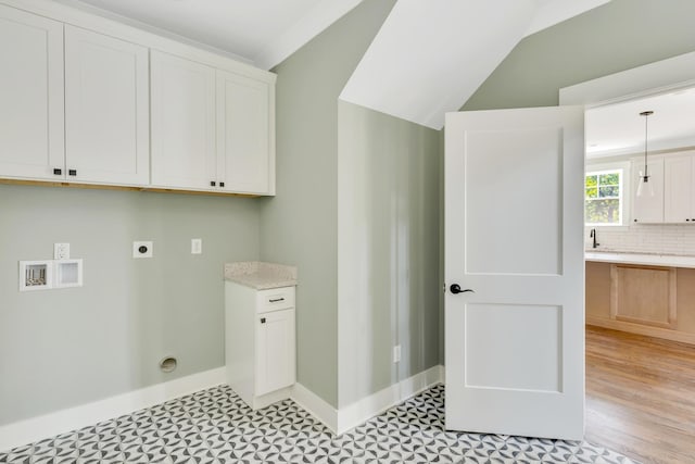 clothes washing area featuring cabinets, hookup for a washing machine, light hardwood / wood-style floors, hookup for an electric dryer, and sink