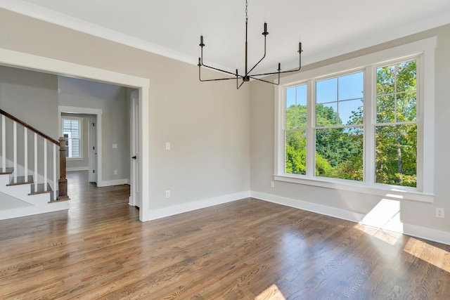 unfurnished dining area featuring ornamental molding, hardwood / wood-style floors, and a notable chandelier