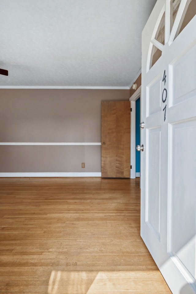 empty room with crown molding and light hardwood / wood-style flooring