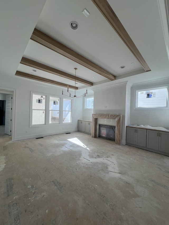 unfurnished living room with a fireplace, beam ceiling, and a wealth of natural light