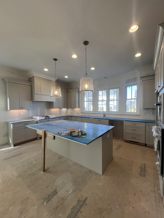 kitchen with a center island, sink, hanging light fixtures, gray cabinets, and ornamental molding