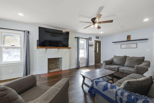 living room with ceiling fan, a healthy amount of sunlight, dark hardwood / wood-style floors, and a brick fireplace