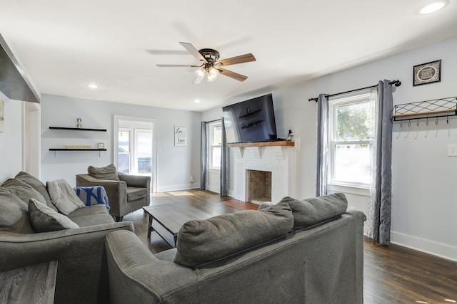 living room featuring dark hardwood / wood-style floors, ceiling fan, a fireplace, and a wealth of natural light