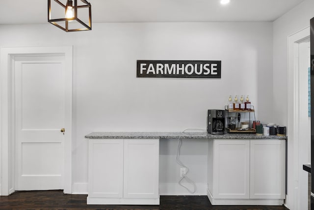 bar with white cabinets, dark hardwood / wood-style floors, pendant lighting, and stone counters