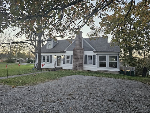 cape cod home featuring a yard