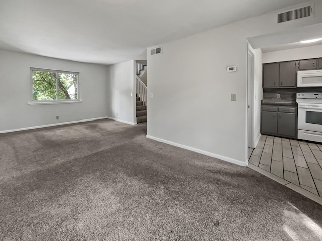 unfurnished living room featuring carpet, visible vents, stairway, and baseboards