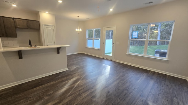 kitchen featuring dark wood-type flooring, a kitchen breakfast bar, sink, hanging light fixtures, and a chandelier