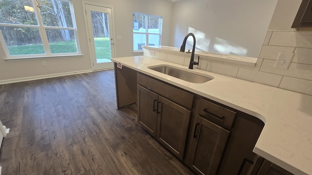 kitchen with dark brown cabinets, dishwasher, sink, and dark wood-type flooring