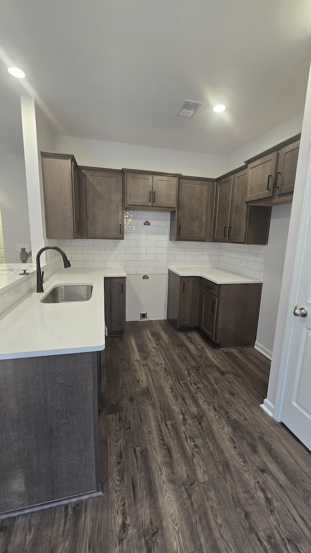 kitchen with dark hardwood / wood-style flooring, dark brown cabinetry, sink, and decorative backsplash