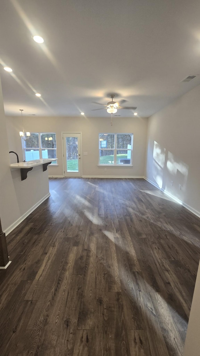 unfurnished living room featuring dark wood-style floors, visible vents, and baseboards