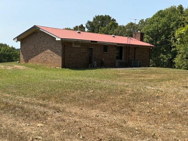 back of property featuring cooling unit and a lawn