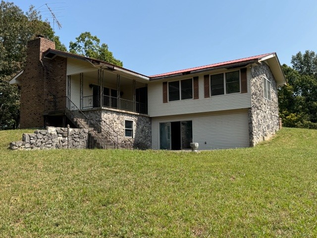 back of property with a balcony and a yard