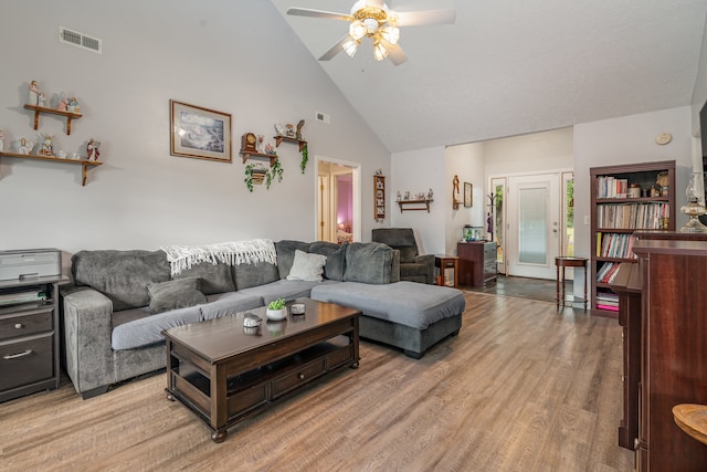 living room with light hardwood / wood-style floors, high vaulted ceiling, and ceiling fan